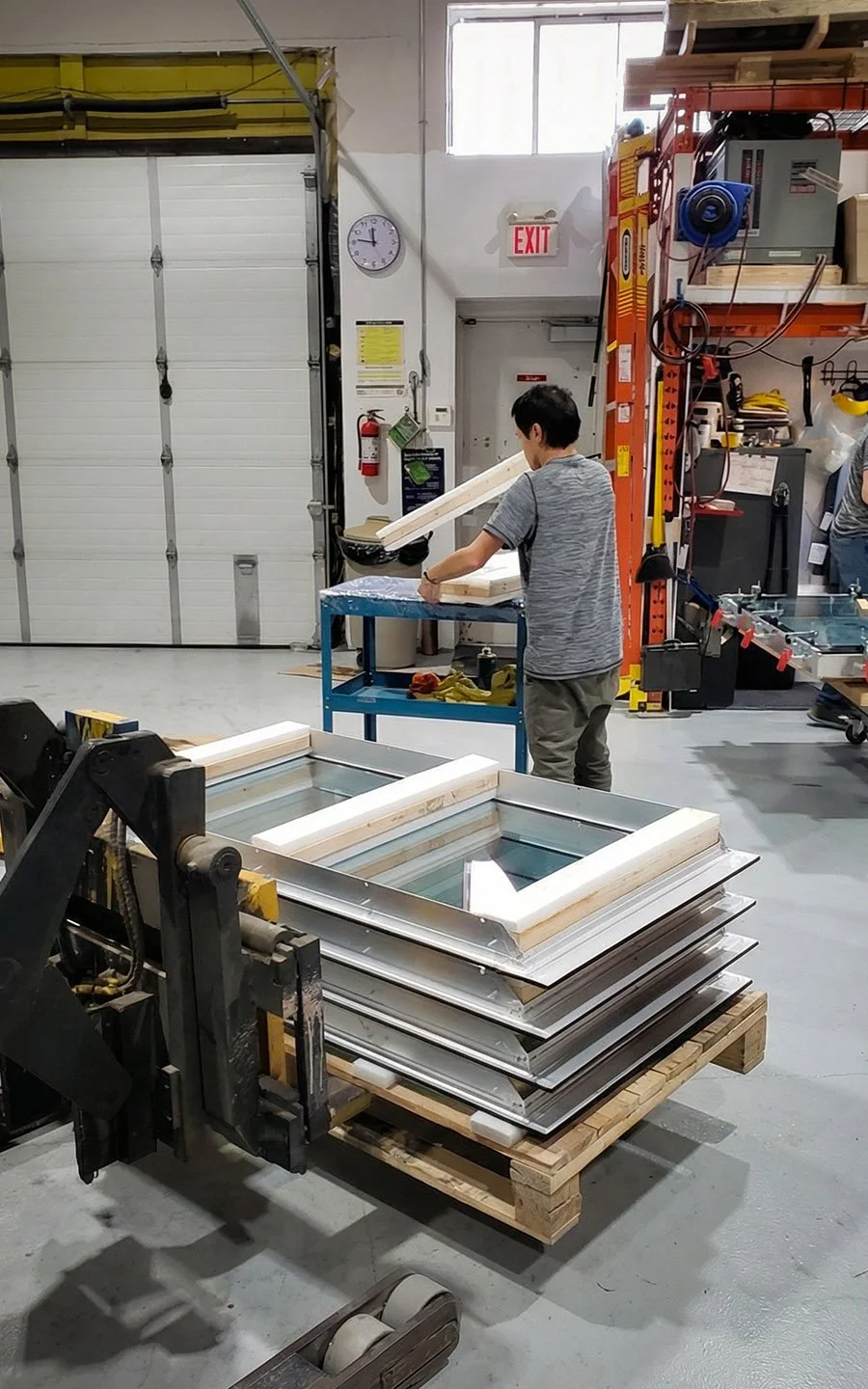 Technician preparing signage components and laminated glass panels for indoor digital signage assembly at B&F Solutions Inc.