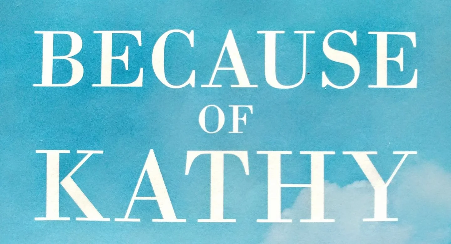 A blue sky with clouds and the text 'Because of Kathy' written in white.