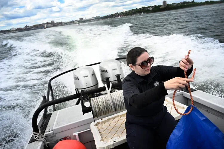 A woman in sunglasses on a boat, holding a rope, with two Honda outboard motors and cityscape in the background.