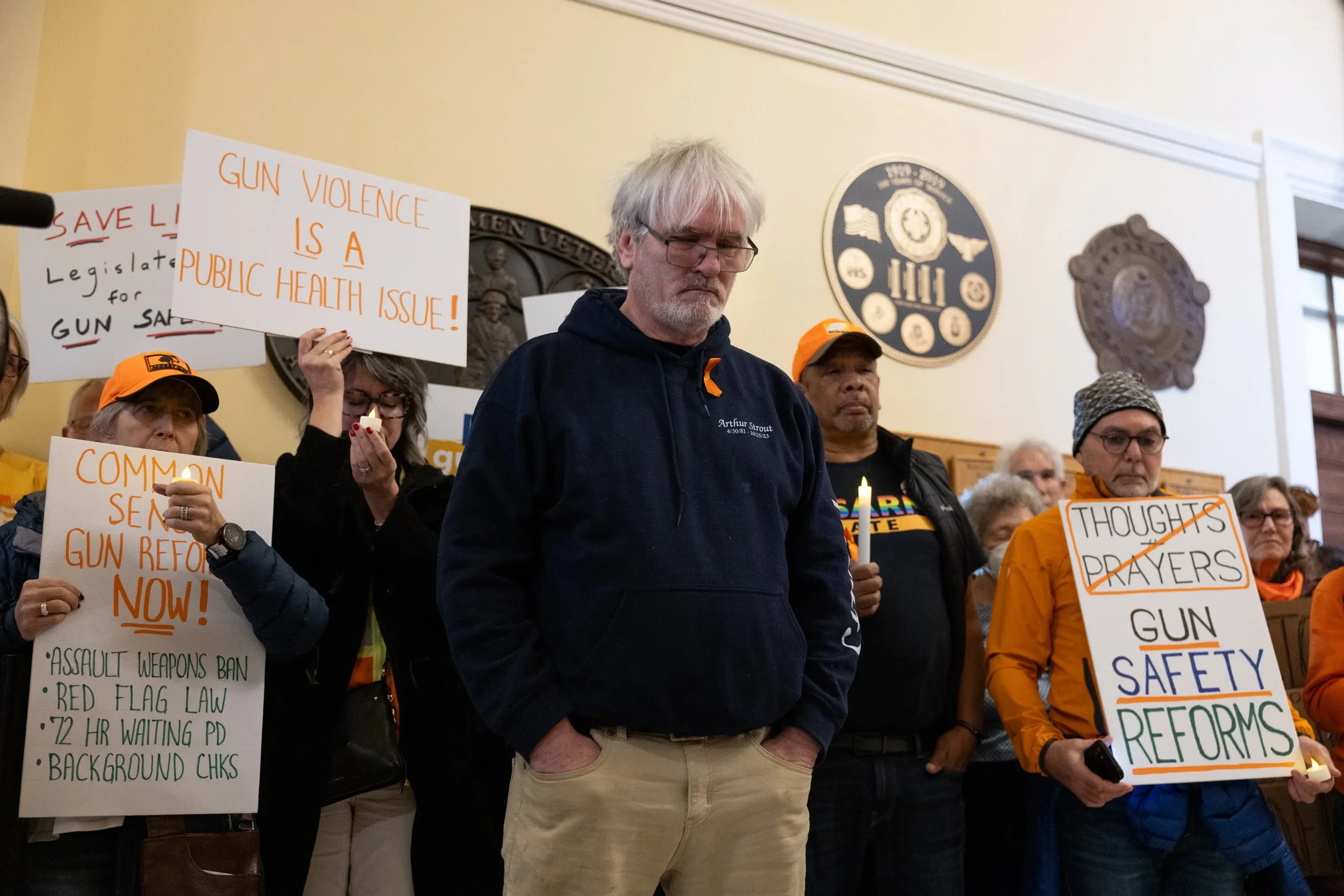 Group of people holding signs and candles during a protest for gun safety and reform.