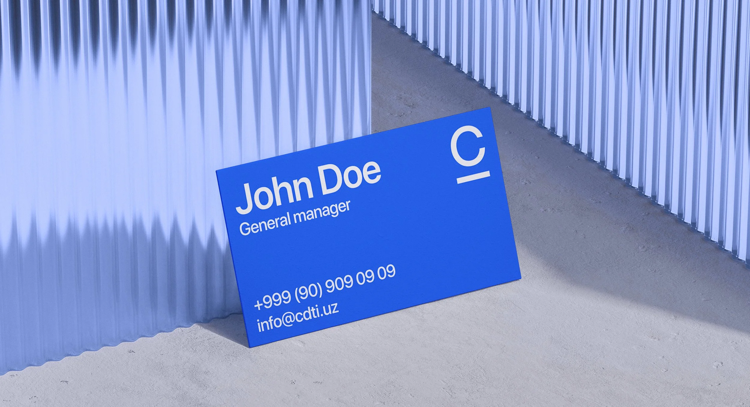 Blue business card on the ground with the name John Doe, title General Manager, phone number +999 (90) 909 09 09, and email info@cdti.uz