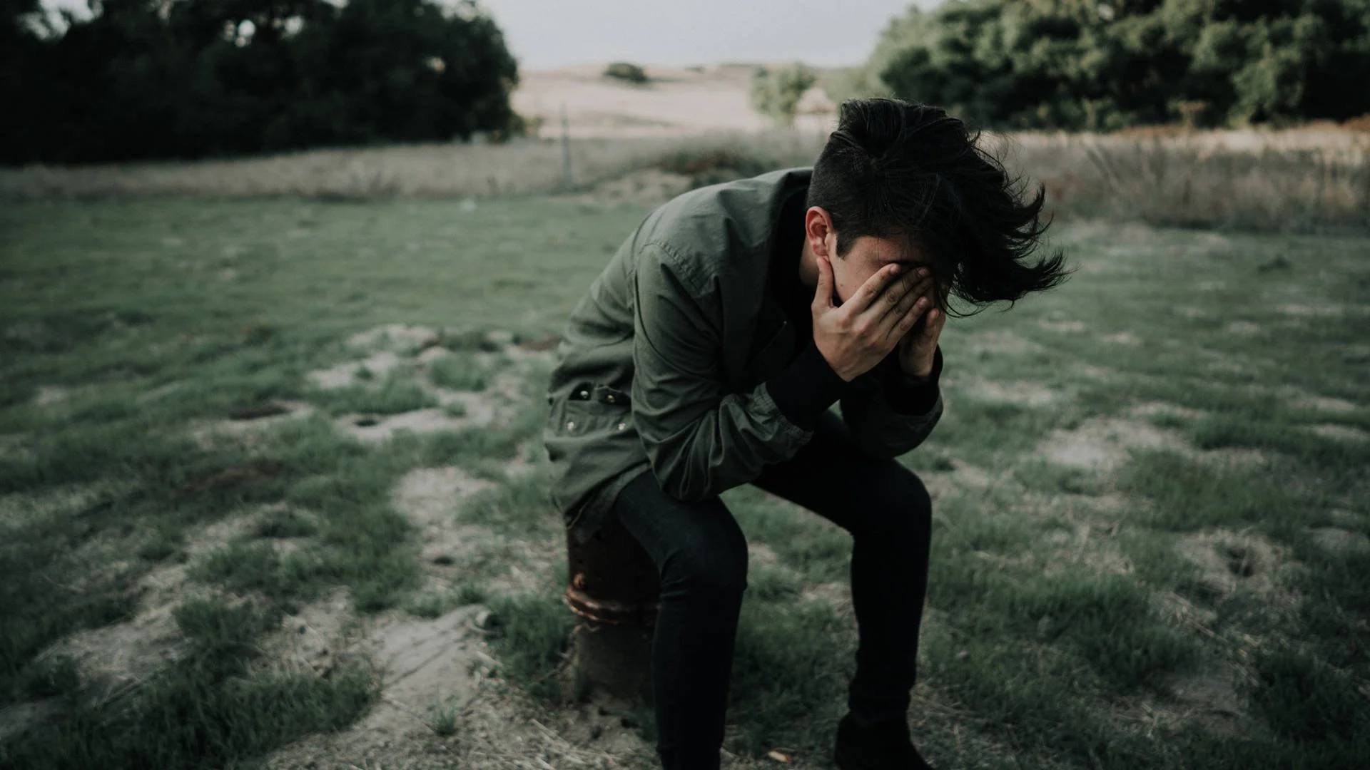 Sad man weeps in a field.