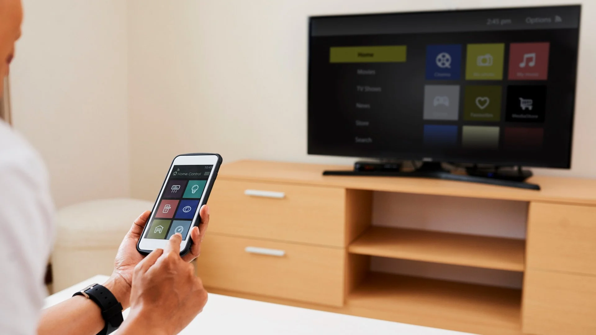 Guy watching TV while on his phone.