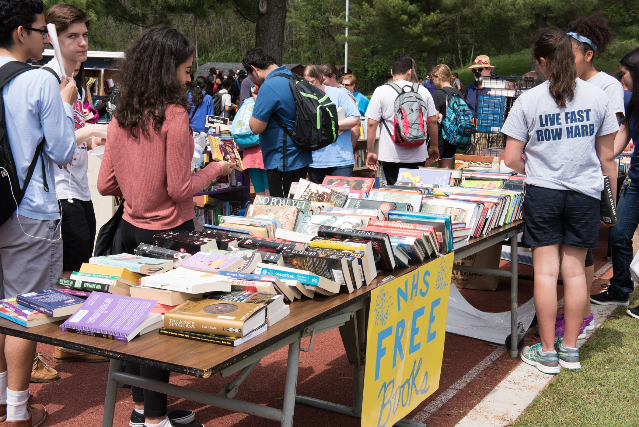 People browsing through tables of free books at an outdoor book sale event.