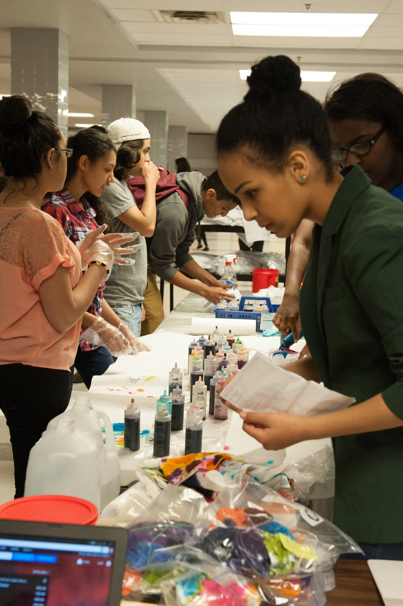 People participating in a workshop at a long table with bottles of colorful ink and supplies.