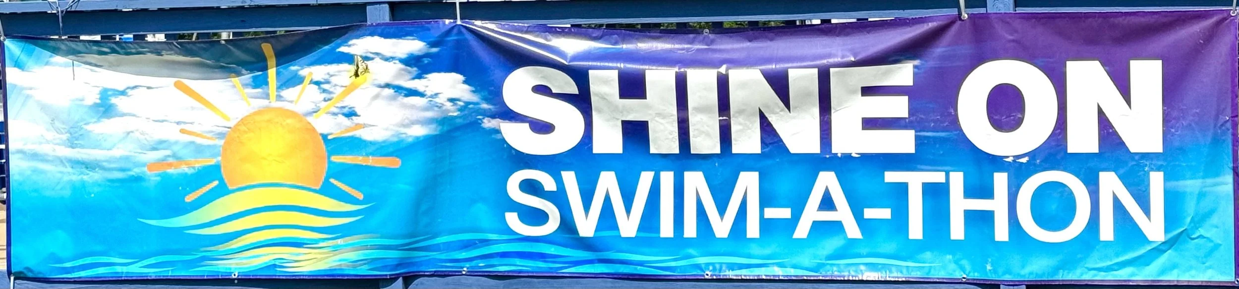 Banner with a sun and water illustration and the text "Shine on Swim-A-Thon" for a swimming event.