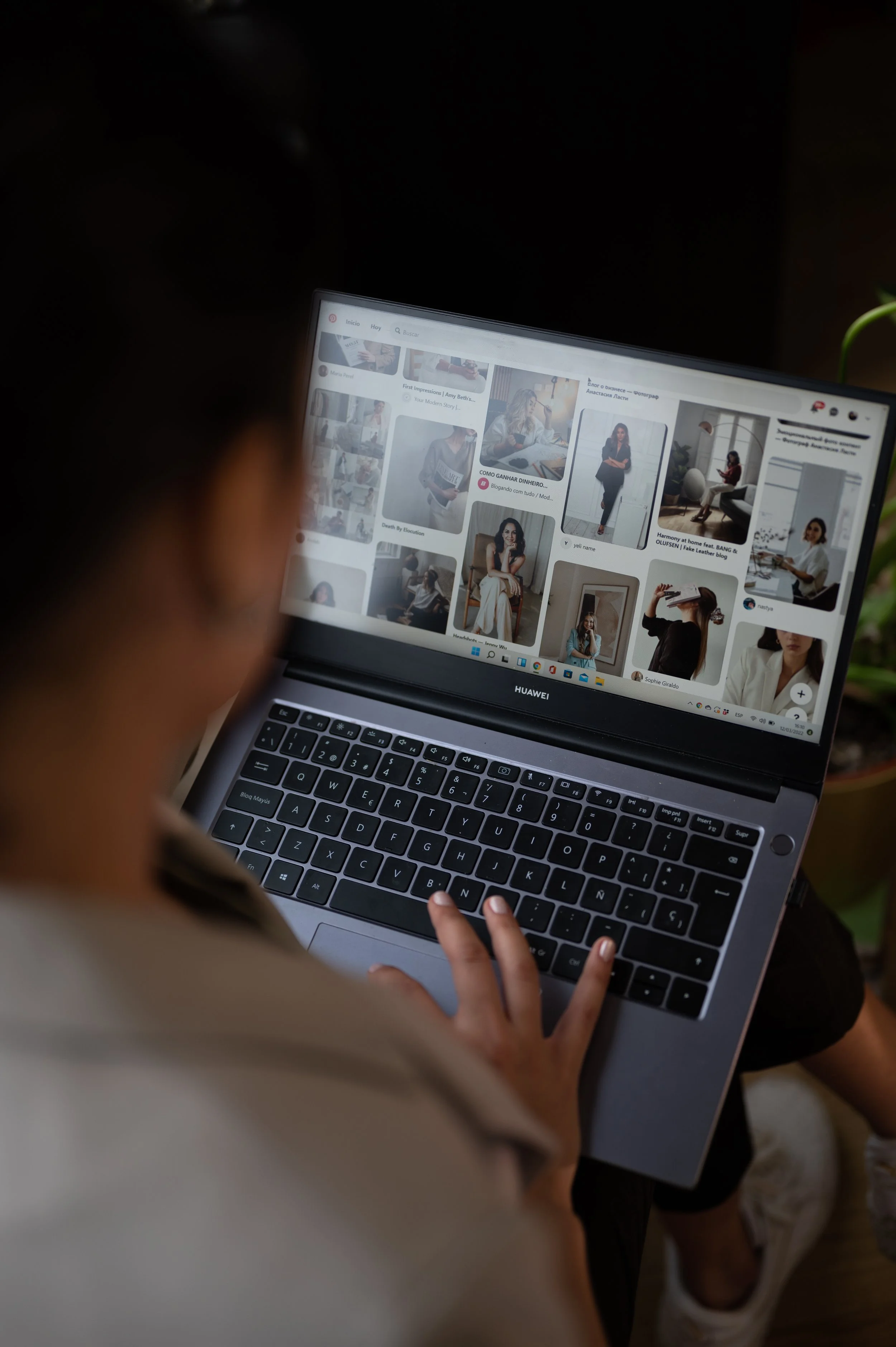 Person browsing Pinterest on a laptop, viewing a page with various photos of women in different poses and settings.