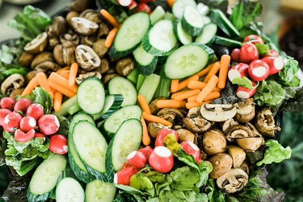 Fresh vegetables including sliced cucumbers, carrots, mushrooms, radishes, and lettuce.