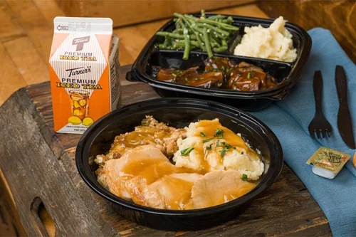 Roasted turkey and gravy over mashed potatoes in a Goose Express to-go bowl