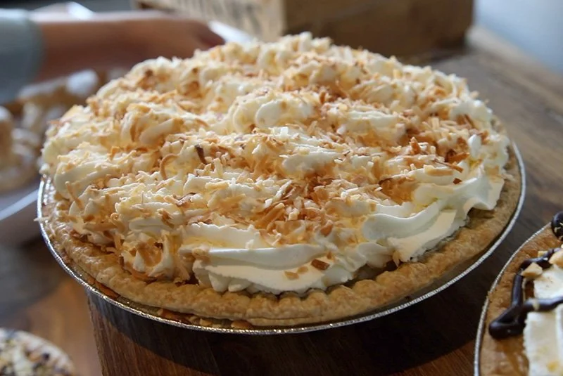 Pie topped with whipped cream and toasted coconut flakes