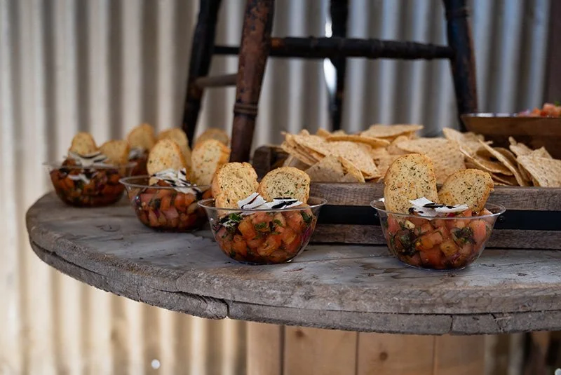 Vegetable salsa served in small glass bowls with crostini on a rustic wooden table.