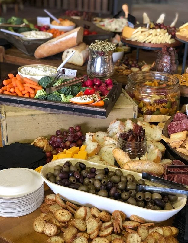 A cheese and charcuterie spread with crackers, grapes, olives, and various cheeses.