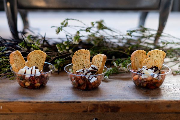 Three small glass bowls with dessert, topped with cookies and chocolate shavings on a wooden surface.