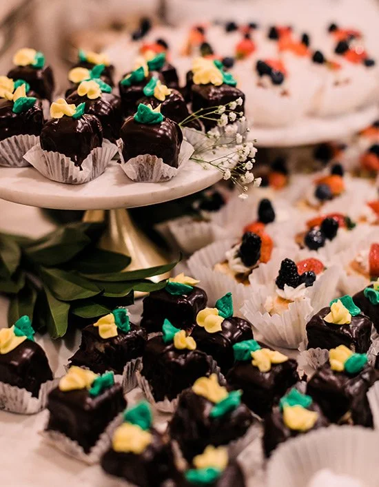 Assorted decorated mini cupcakes and brownies on a tiered stand for a party or celebration.