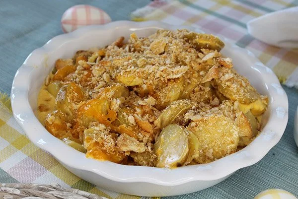 Baked vegetable casserole with bread crumbs in a white bowl on a checkered tablecloth
