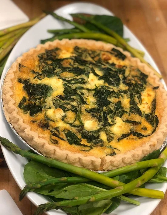 Vegetable quiche with spinach and cheese, served with green beans on a white platter.