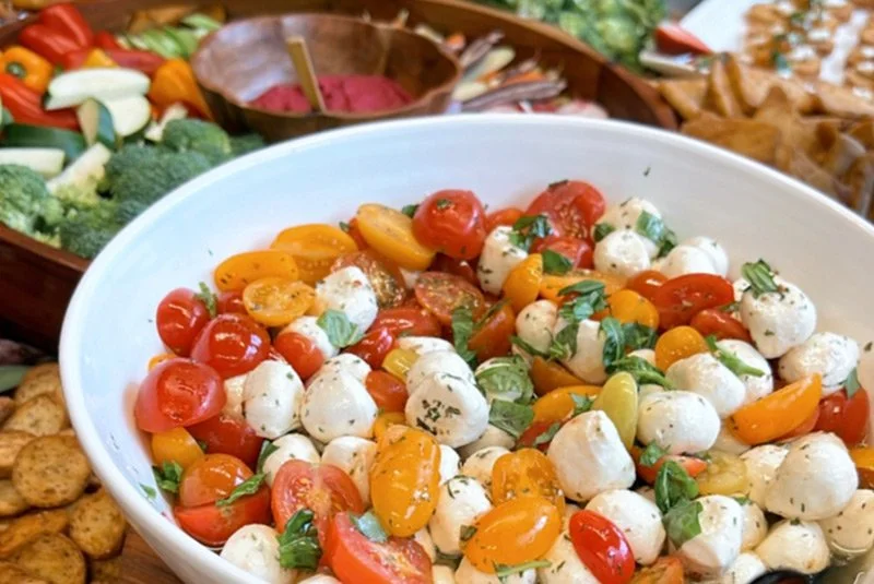 Caprese salad with cherry tomatoes, mozzarella balls, and basil in a white bowl