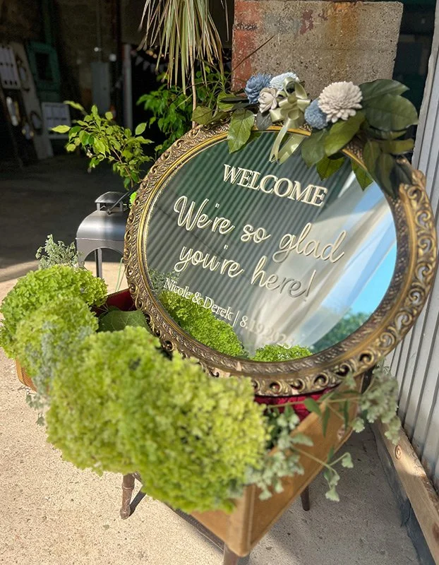 Decorative welcome sign with floral arrangement reflecting a garden or outdoor setting.