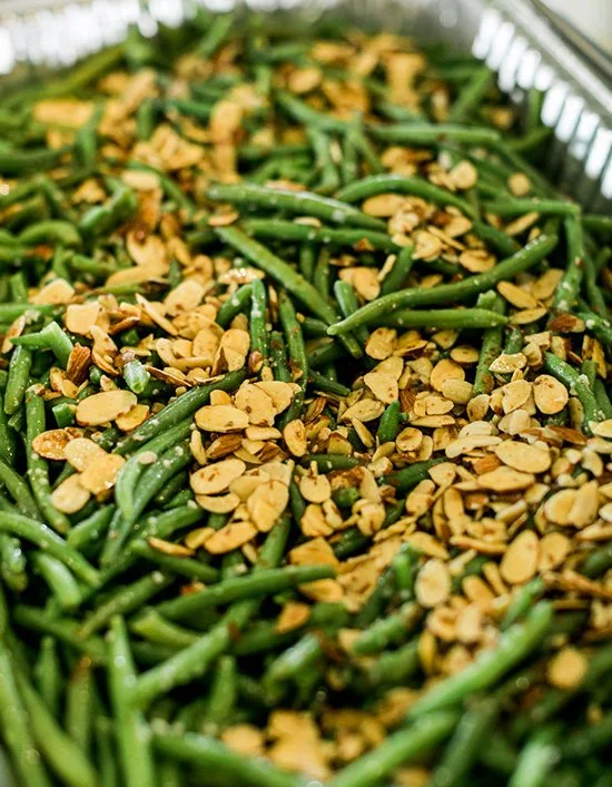 Green beans topped with sliced almonds in a baking dish.