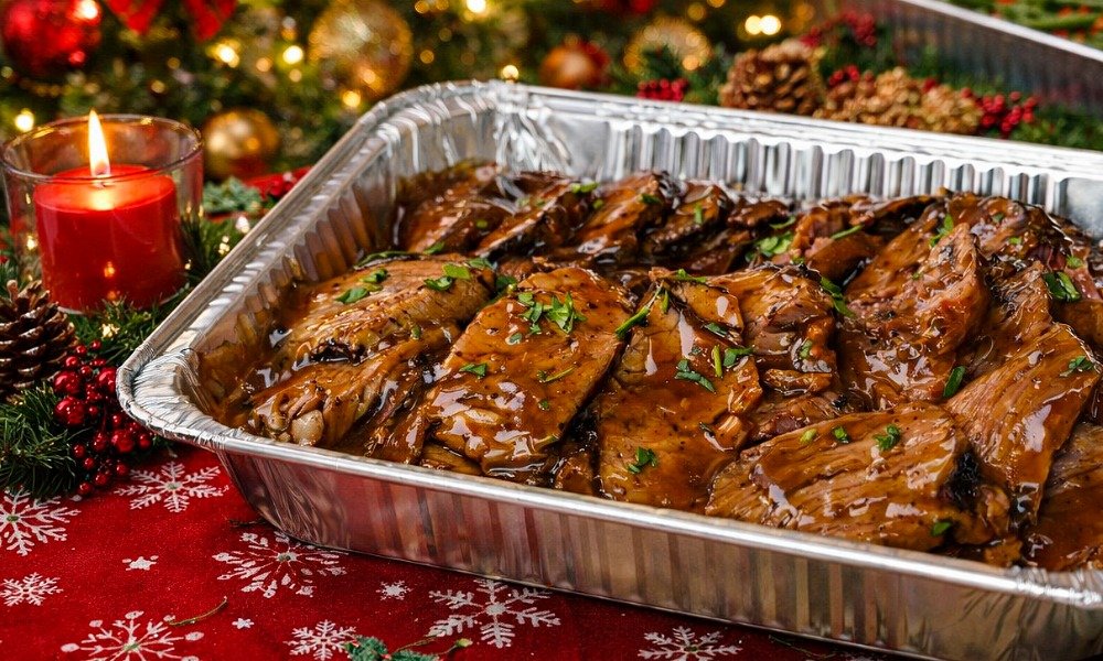 Barbecue ribs glazed with sauce, garnished with parsley, on a festive table with Christmas decorations, including a red candle, pinecones, and ornaments.
