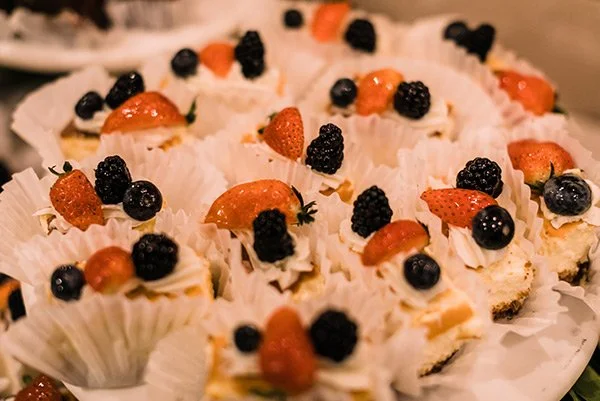 Assorted mini fruit-topped cheesecakes with strawberries, blackberries, and blueberries.