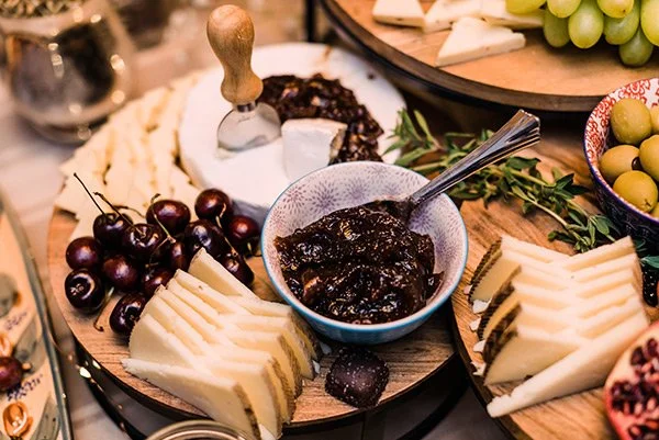 Cheese and grape platter with jam in a bowl, on a wooden table.