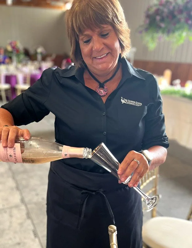 A woman pouring Rosé wine into a champagne flute at a celebration or event.