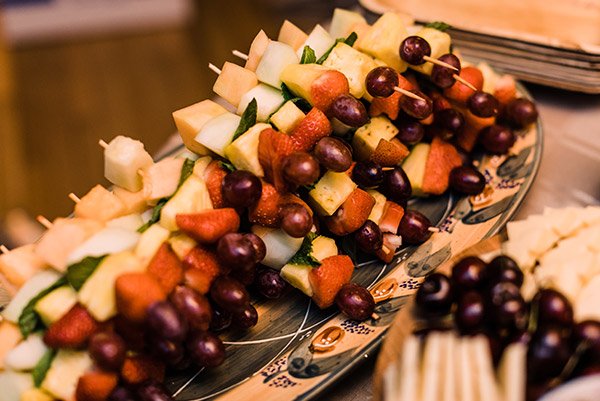 Skewers of assorted fresh fruits on a platter, including grapes, melon, and strawberries.