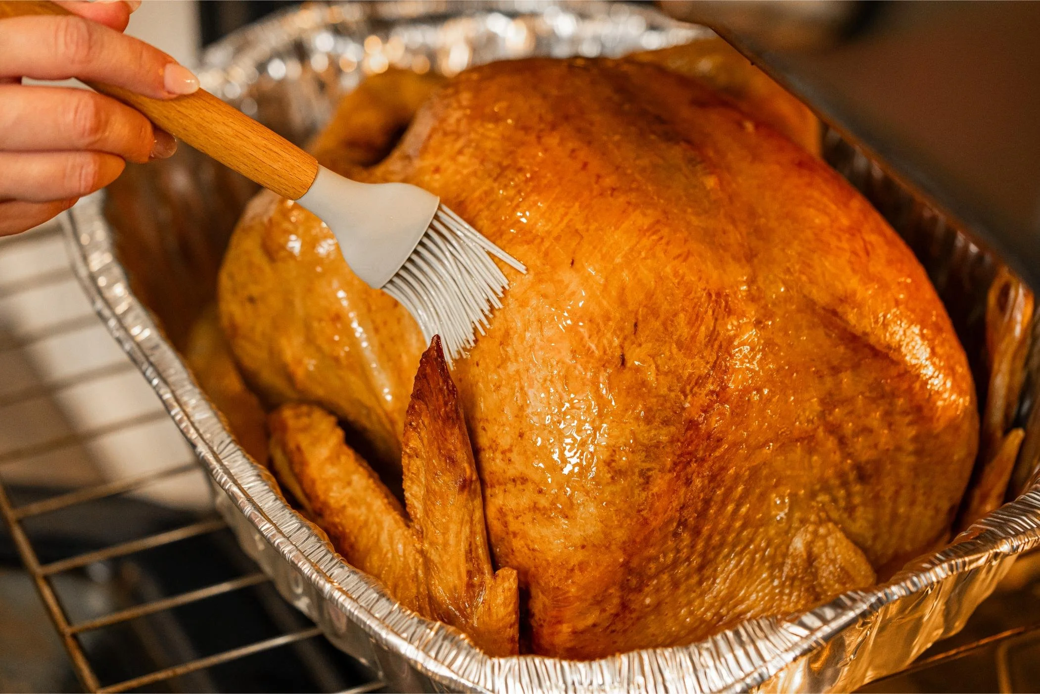 Heat and serve Thanksgiving turkey being basted in its oven-safe pan — Cooked Goose Catering