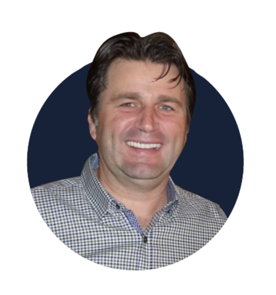 A smiling man with dark hair wearing a checkered shirt against a dark circular background.