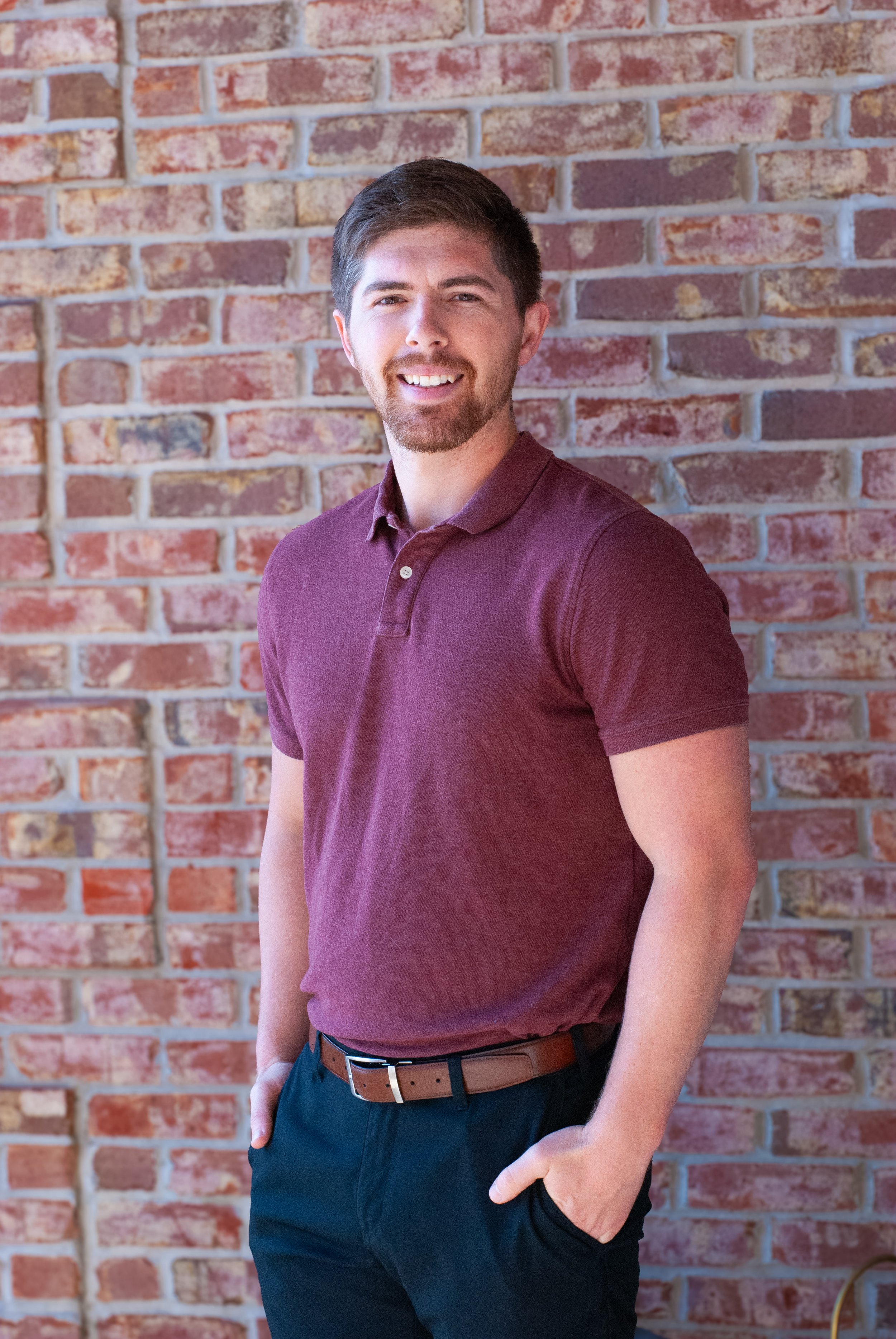 Dr. Talon smiling next to brick wall