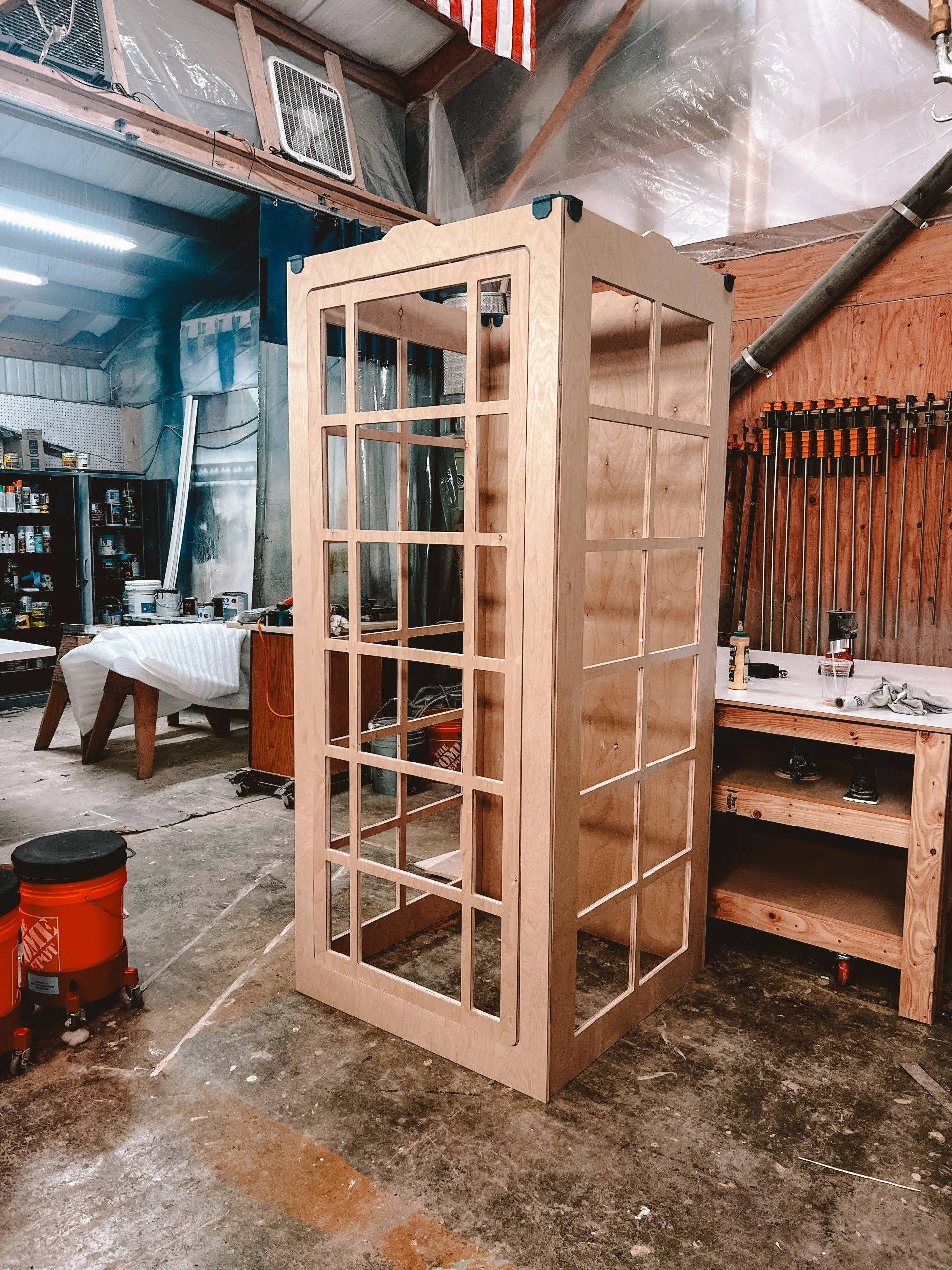 Wooden frame structure with multiple glass-paneled windows in a woodworking workshop.
