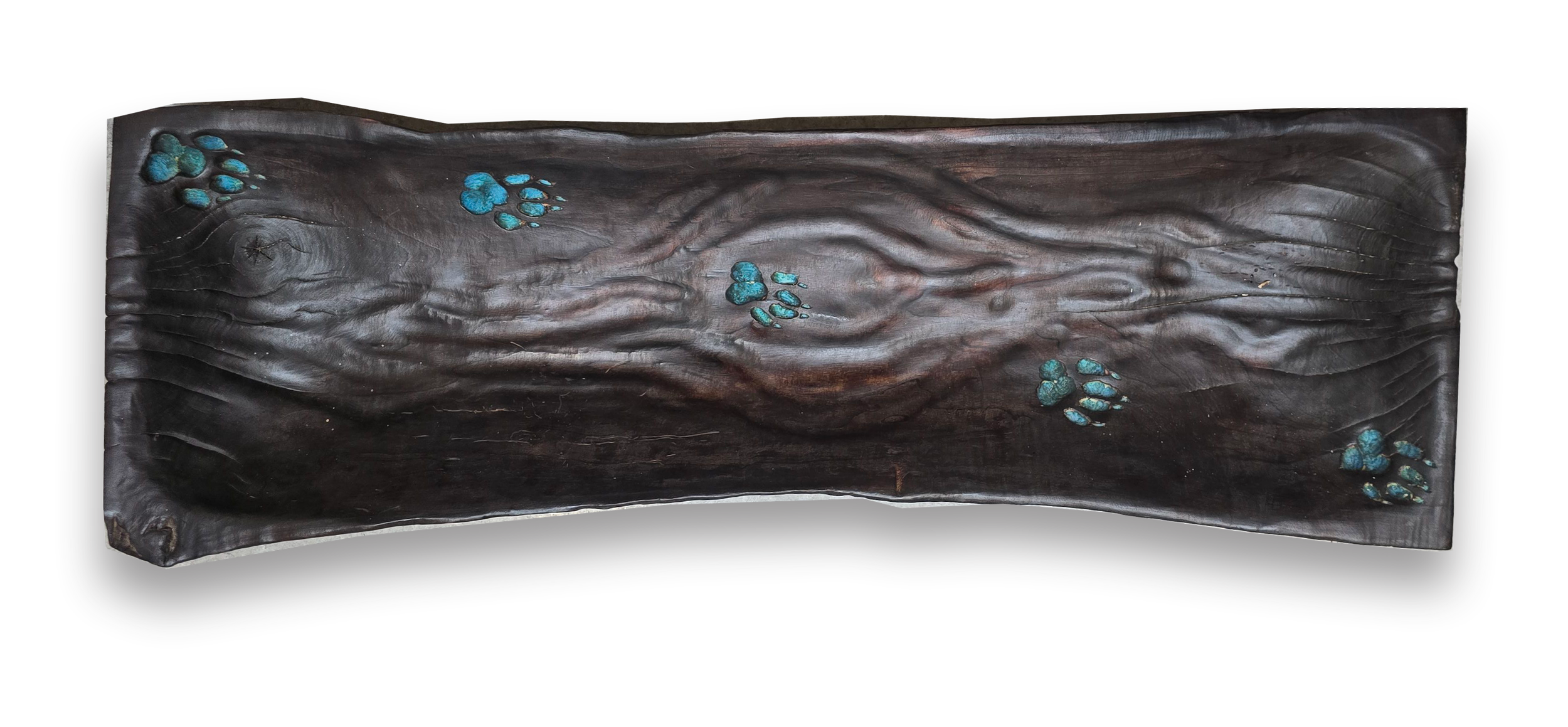 An elongated rectangular wood carving with blue animal paw prints embedded across its surface.
