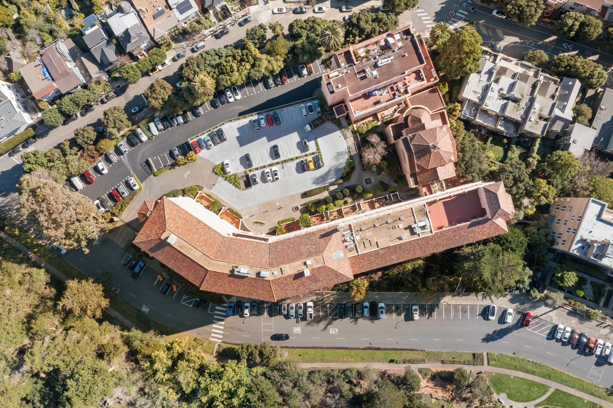An aerial view of a parking lot surrounded by buildings and trees in an urban area.