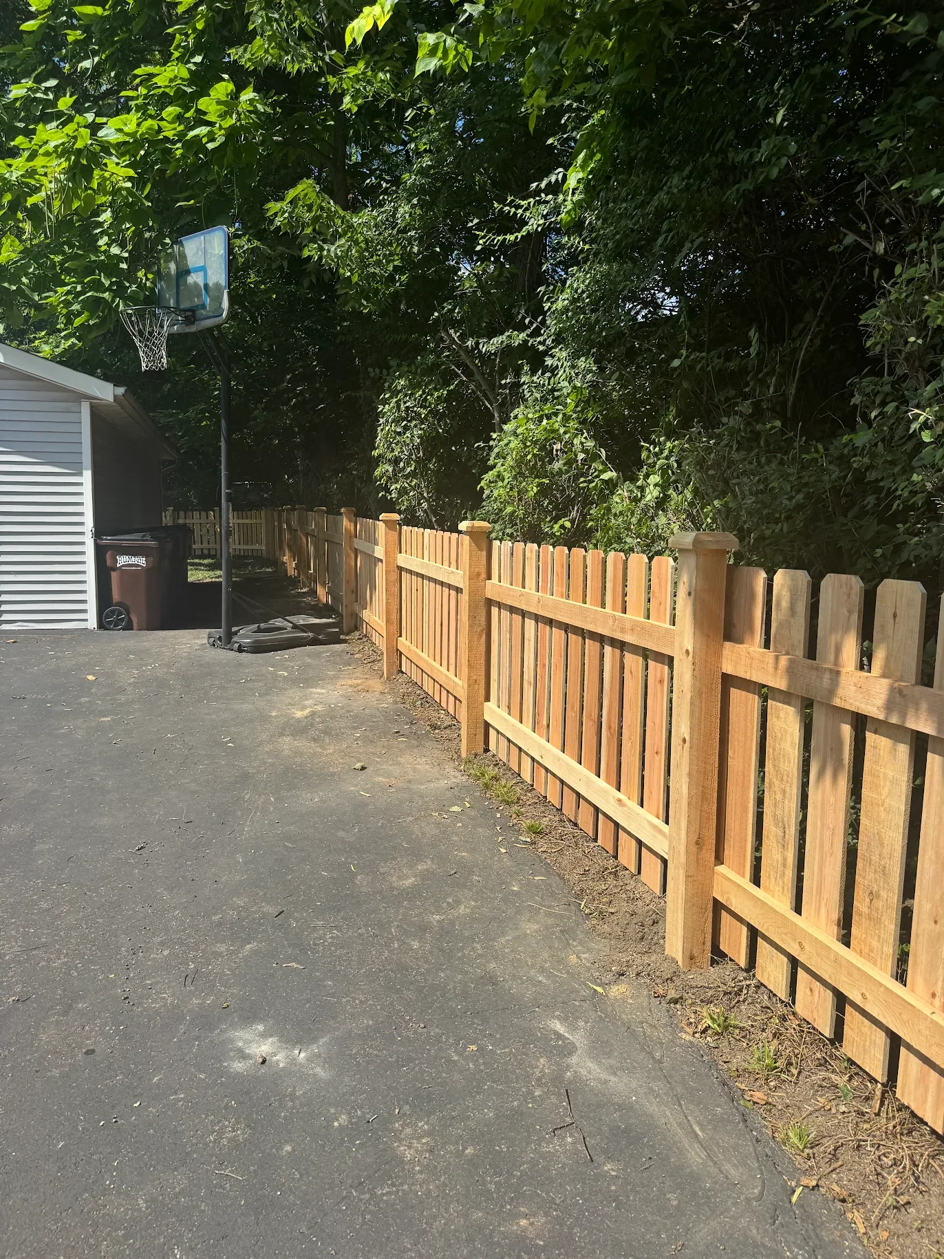 Cedar wooden picket fence around driveway with garage in the background