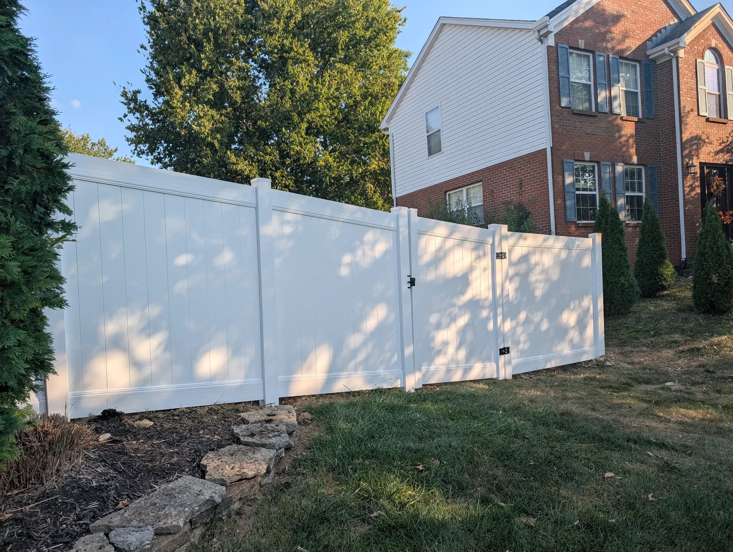 White vinyl privacy fence around a backyard of a brick house in Cincinnati