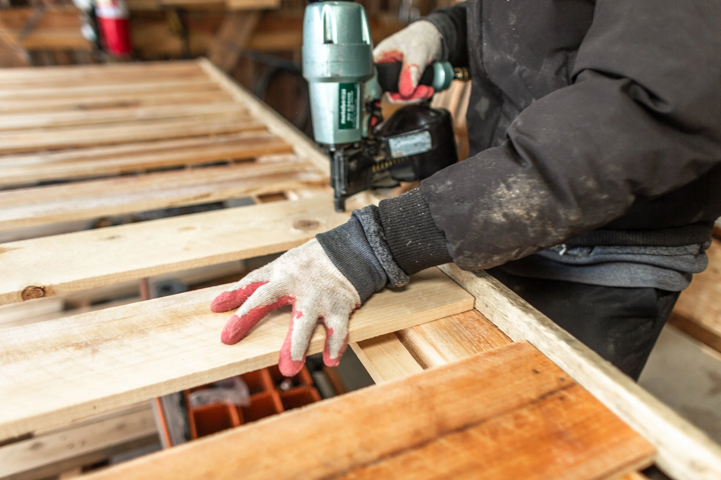 Construction worker at Mae Fence Company nailing a custom-made cedar picket fence in our shop.