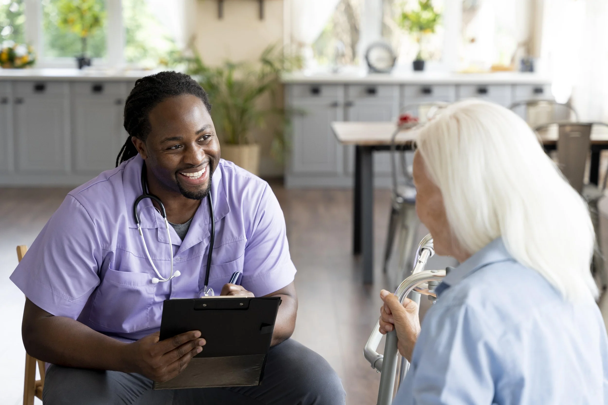 Home health nurse smiling and sitting in front of an elderly client
