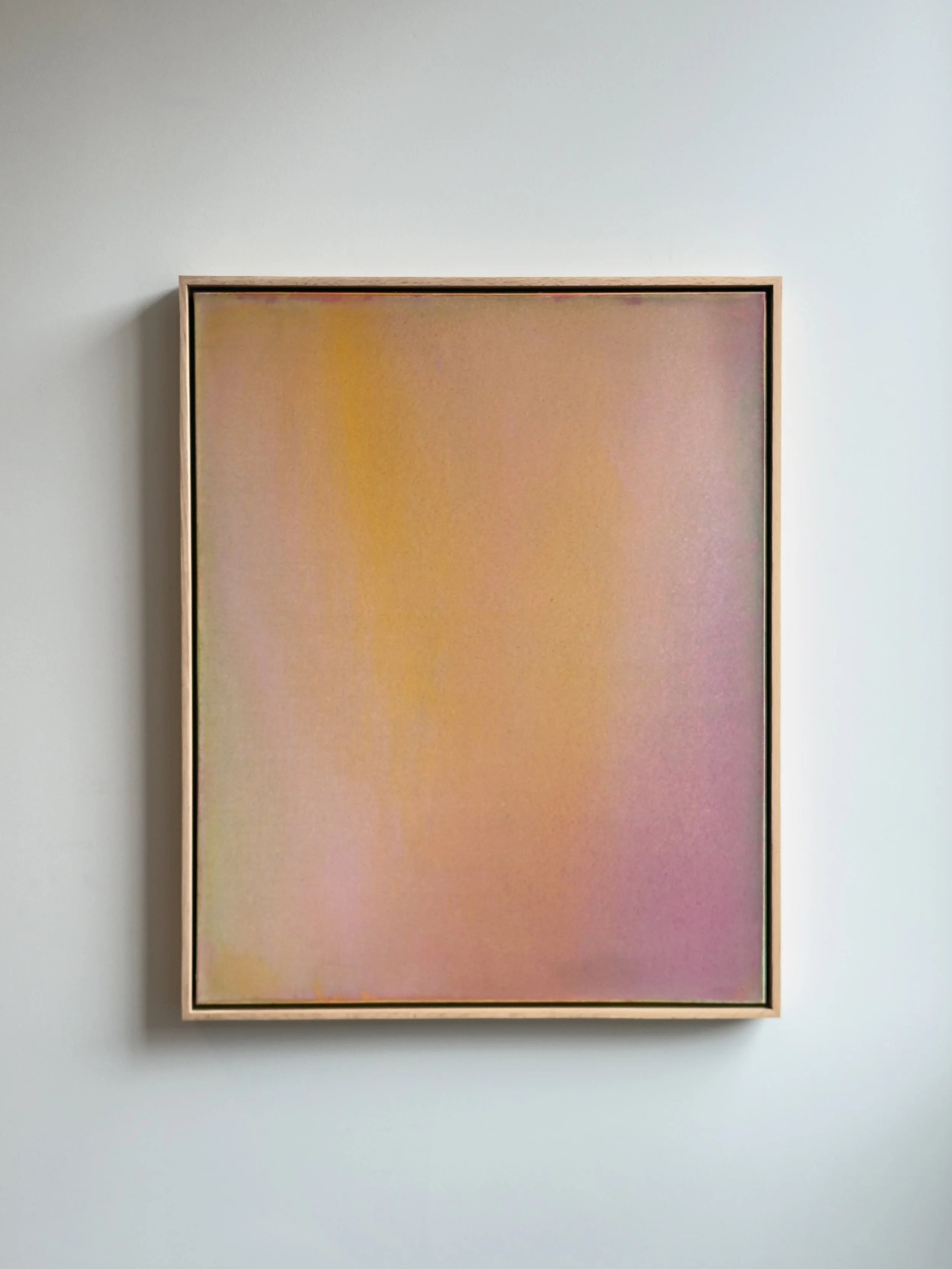 Abstract pastel-colored painting with pink, yellow, and lavender hues in a wooden frame, hanging on a white wall.