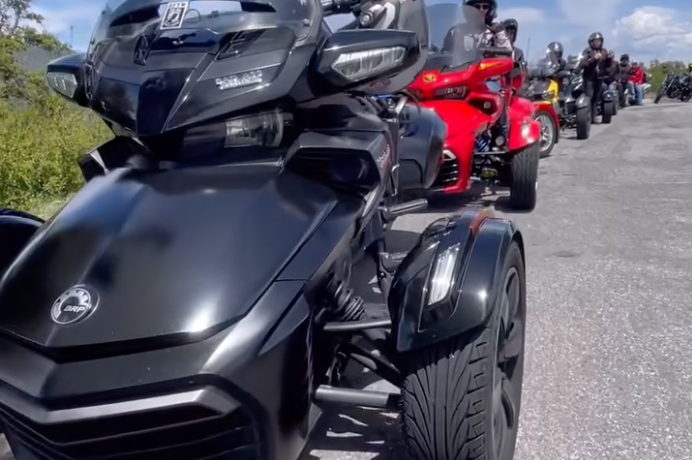 Line of motorcycles and trikes parked on a road.