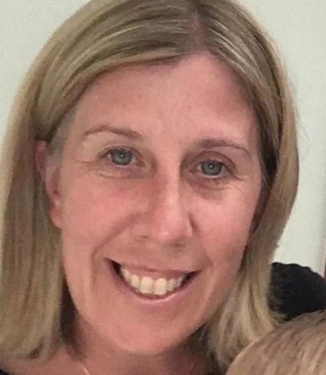 A close-up of a smiling woman with blonde hair and blue eyes.