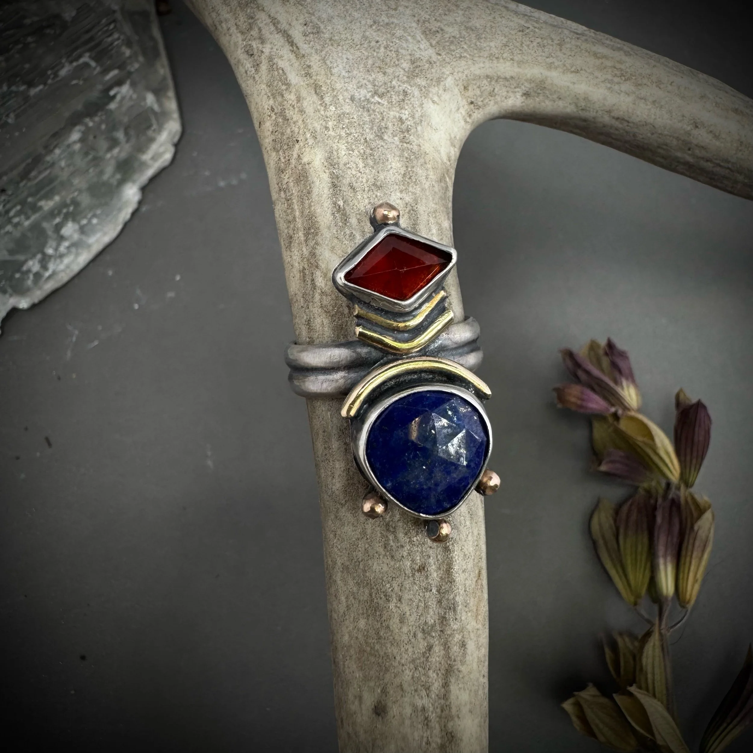 Sterling silver and brass ring with stacked chevron bands, a garnet stone, and a lapis lazuli cabochon