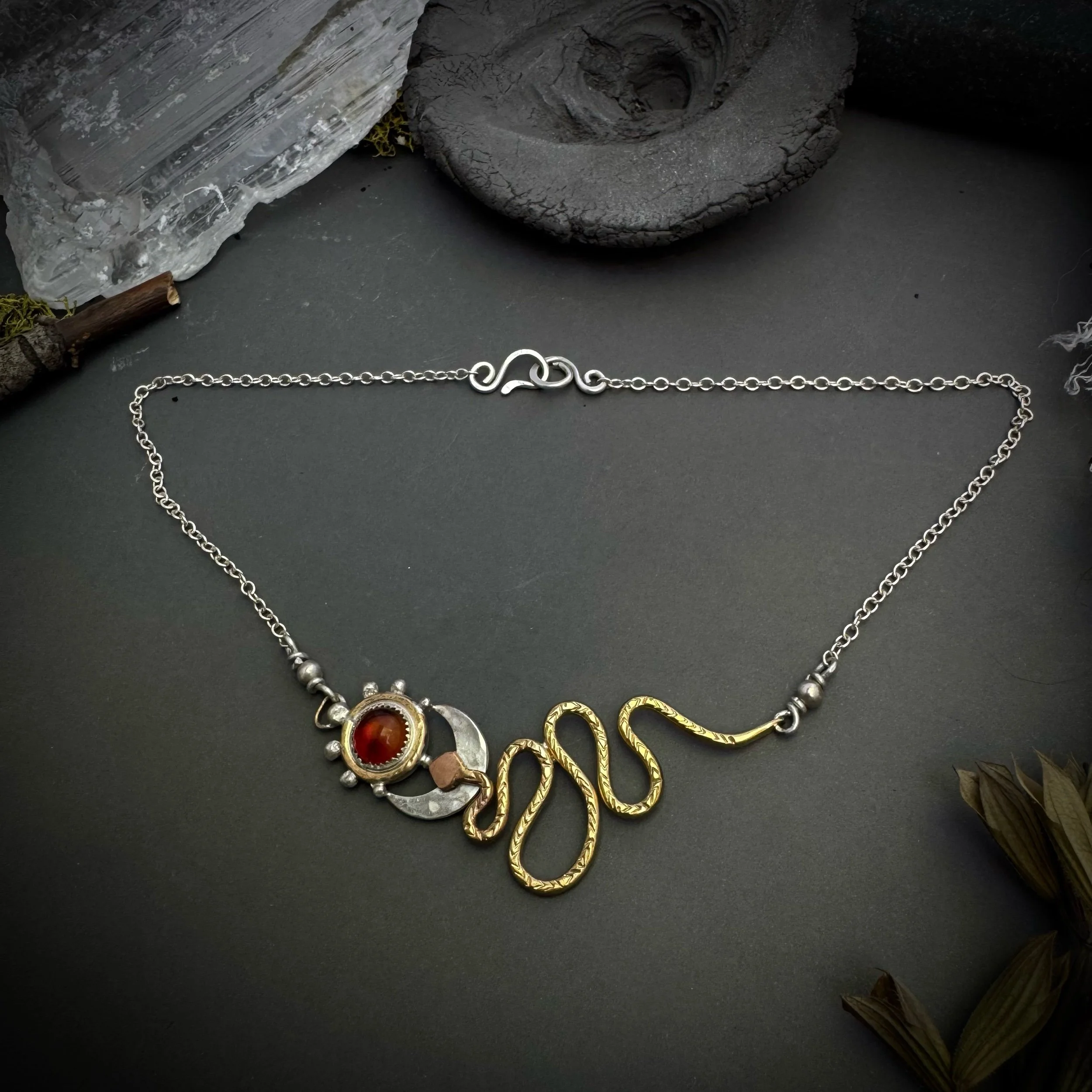 Handcrafted sterling silver and brass necklace with amber cabochon, crescent moon, and hand-formed brass serpent pendant
