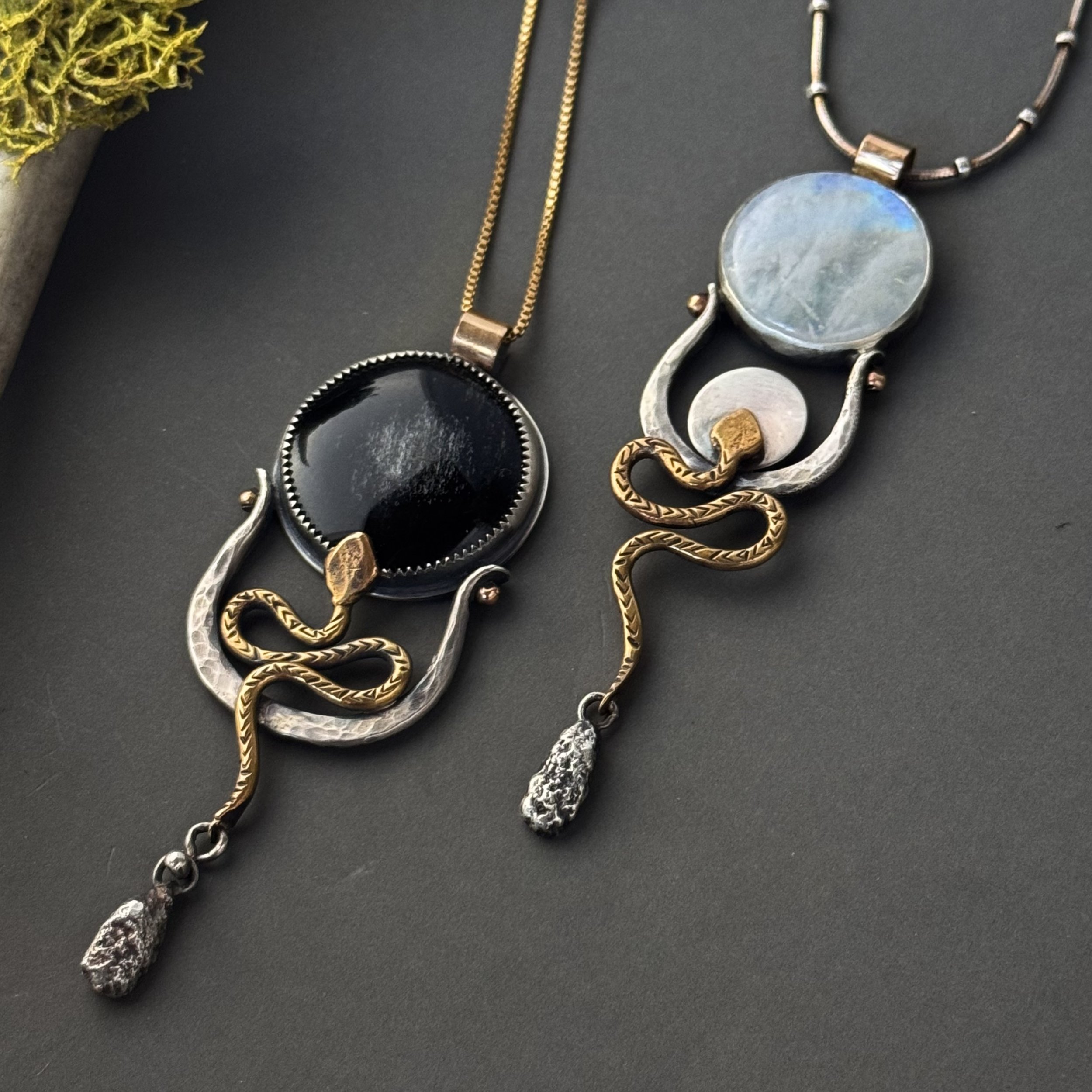 Artisan made necklaces inspired by the divine feminine with large circular gemstones of moonstone and obsidian and serpent motifs, textured metal details, with mixed metals of silver and gold  and recycled silver drops.
