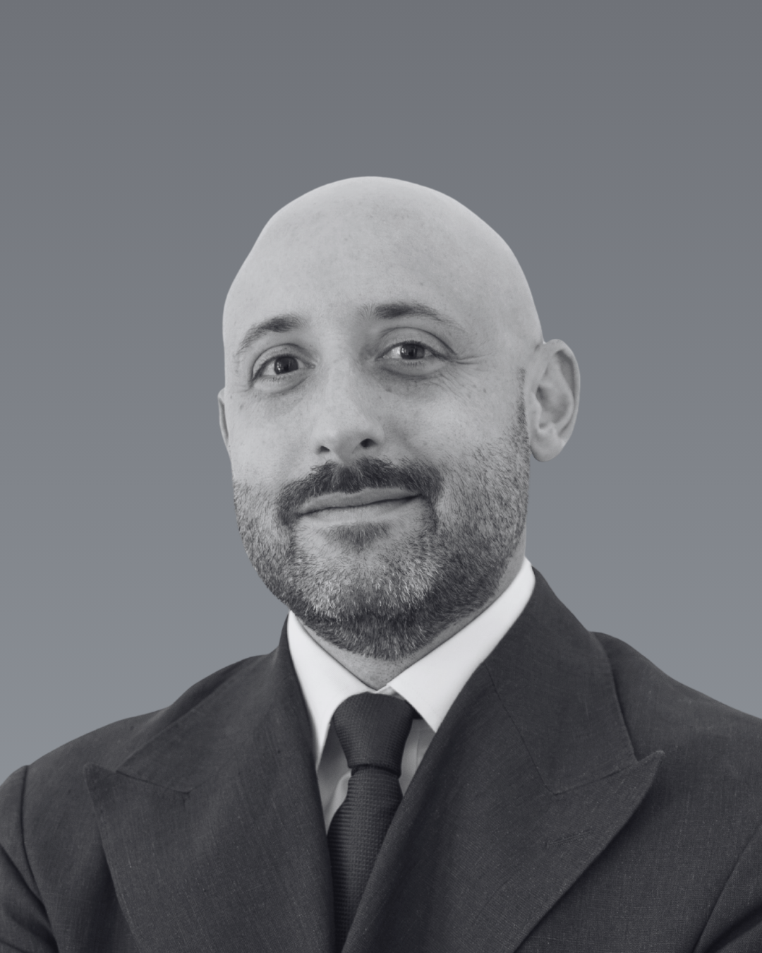 Portrait de Bastien Beaubat portant un costume noir et une cravate noire, avec un fond gris.