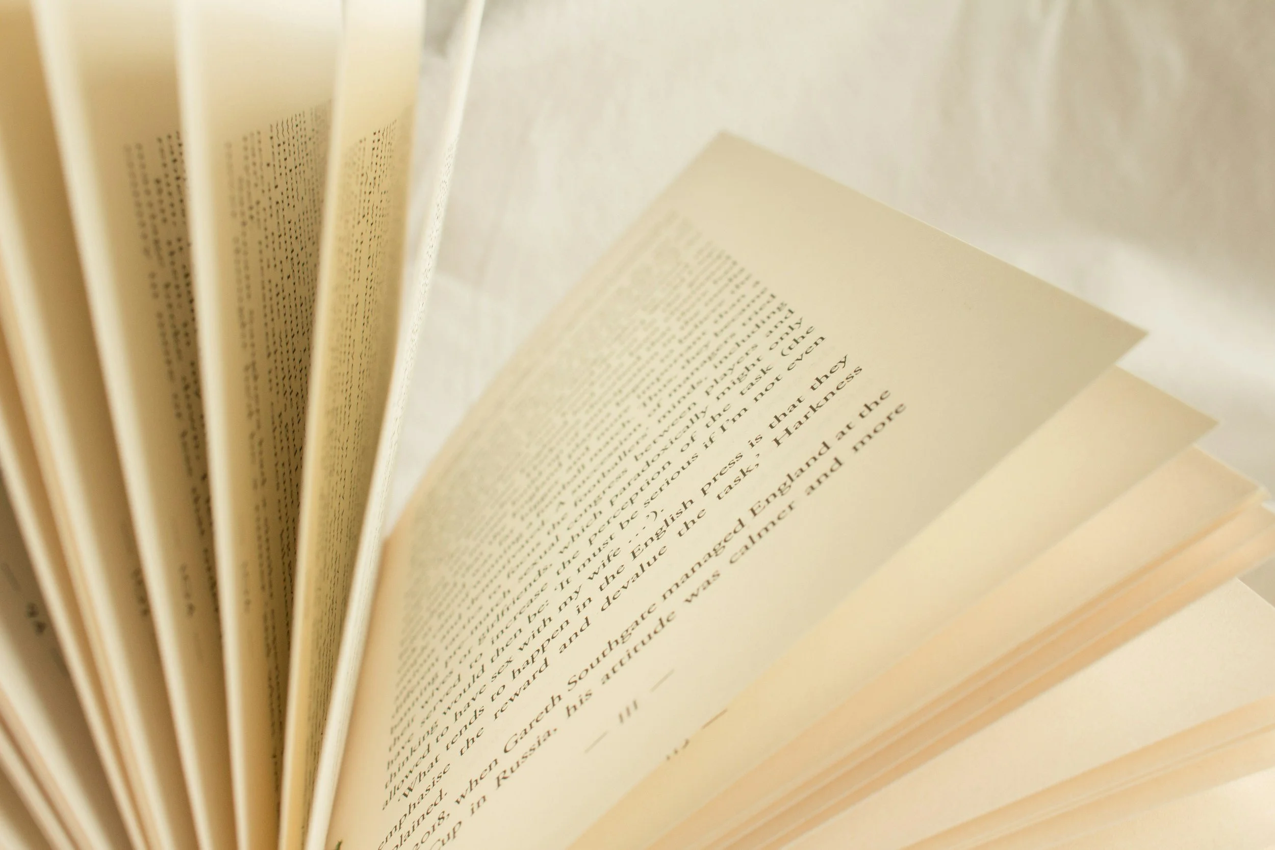 Close-up of an open book showing pages of printed text, with the pages fanned out.