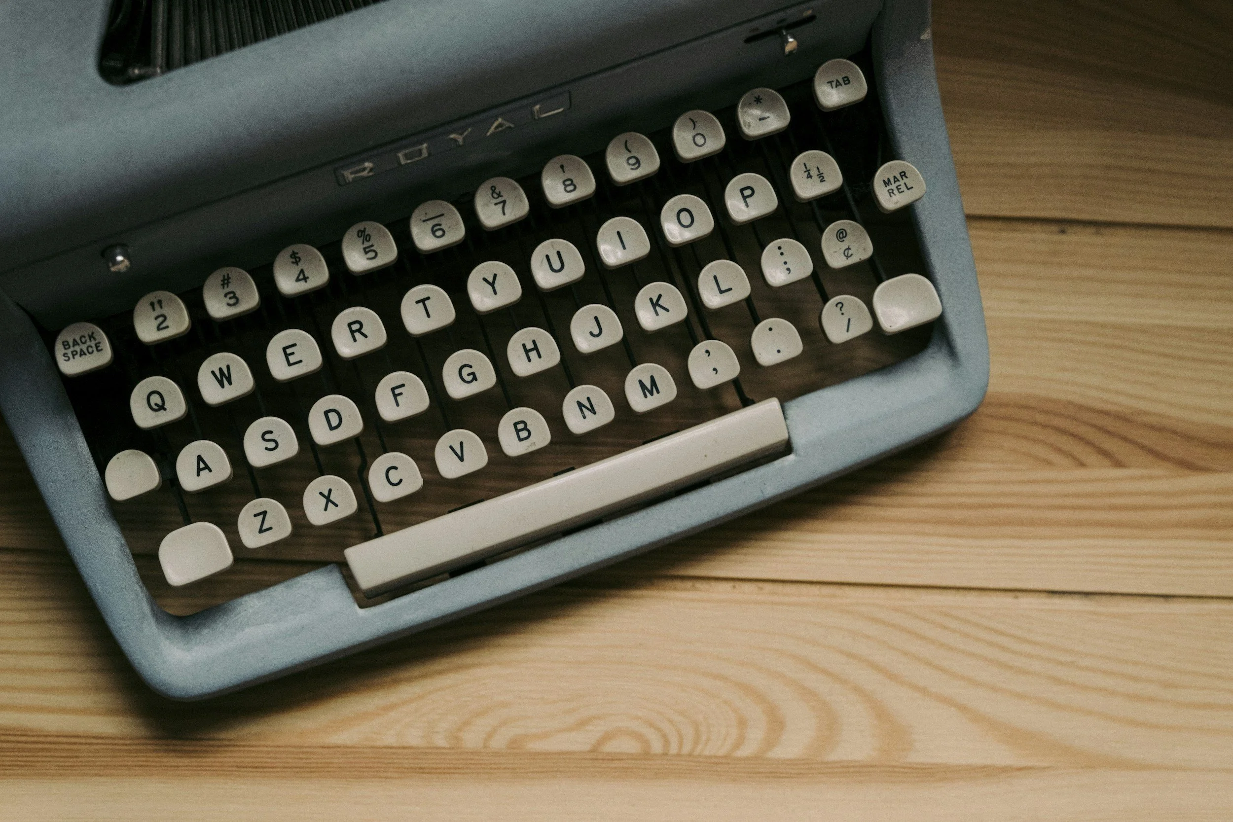 A vintage typewriter with white keys placed on a wooden surface.