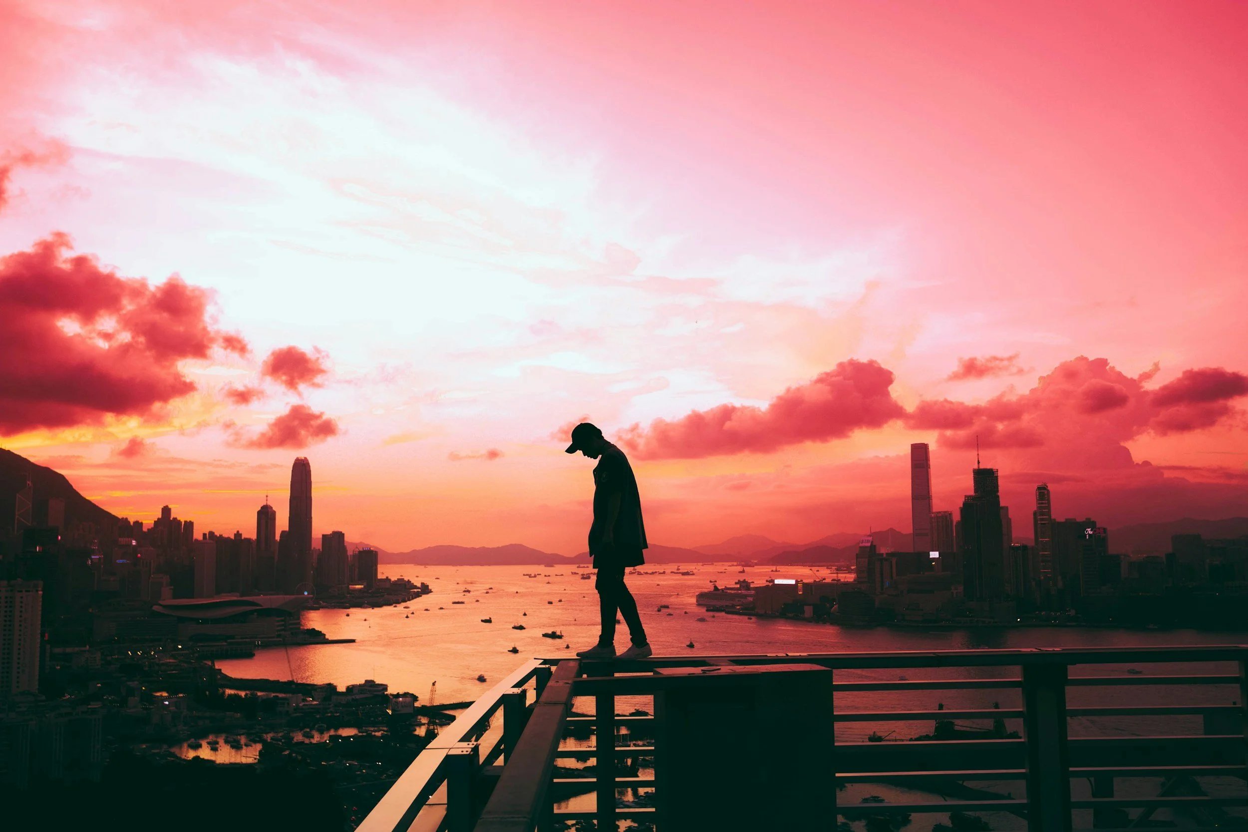 Silhouette of a person standing alone on a rooftop ledge deep in thought.