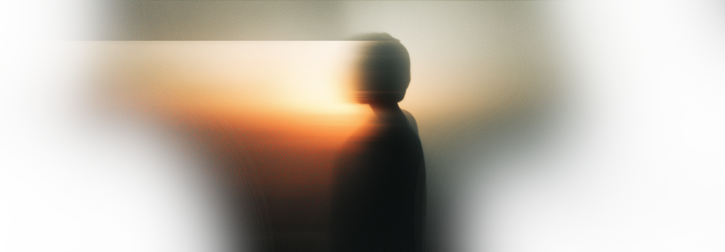 An abstract image with soft focus and warm tones, featuring a silhouette of a person in front of a bright light source.