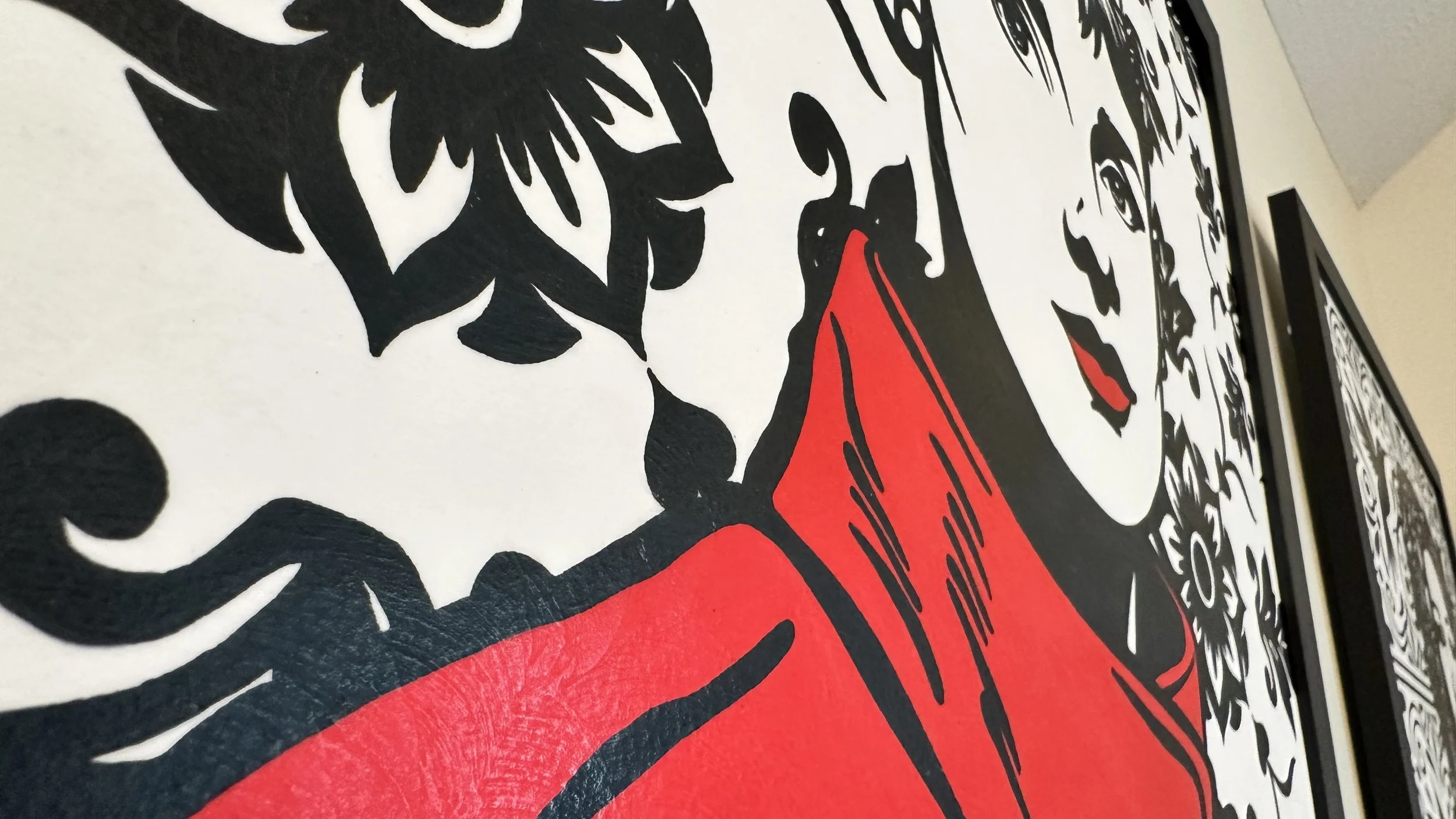 Original framed painting titled Audrey in Red featuring a pop art portrait of Audrey Hepburn in profile with large earrings and a red dress against a geometric pattern by Omaha artist.